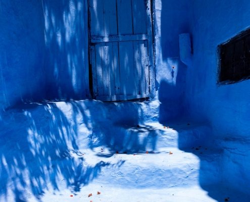 chefchaouen: porta blu, petali rossi sui gradini