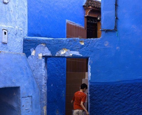 ragazzino gioca a calcio nella città blu del Marocco